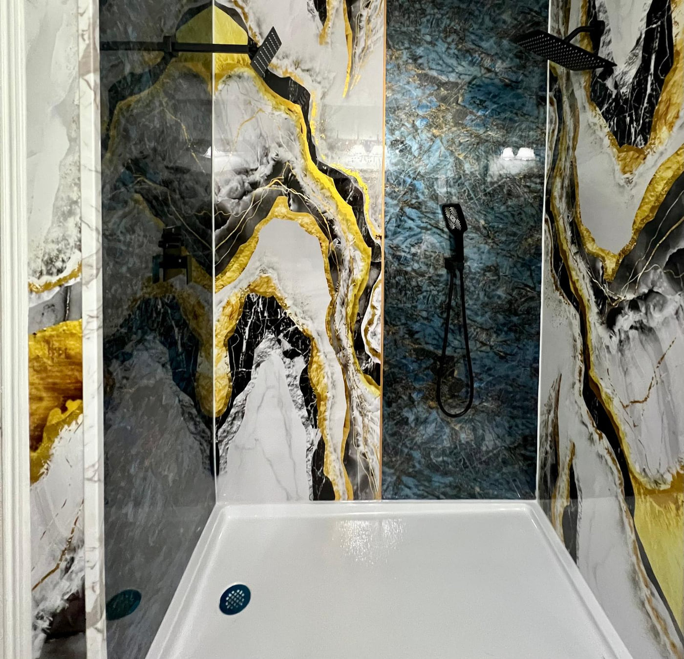 Shower with glossy black, white and gold wall panels, a blue accent panel and matte black fixtures
